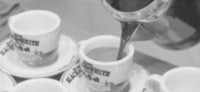 a black and white photo of coffee being poured into cups